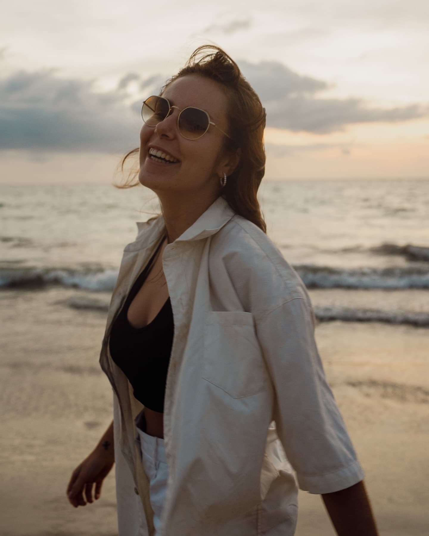 Portrait of a smiling woman in sunglasses on the coast at sunset